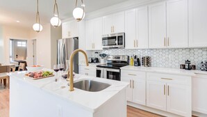 A modern kitchen with white cabinets, stainless steel appliances, and a marble island.