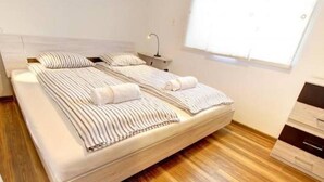 Een moderne slaapkamer met een groot bed, strepen beddengoed en een houten vloer.
