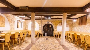 A long dining hall with stone walls and wooden tables and chairs.