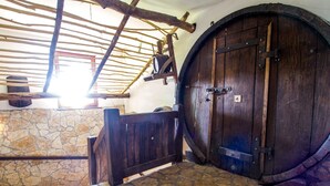 A stone-walled room with a wooden door and a large barrel.