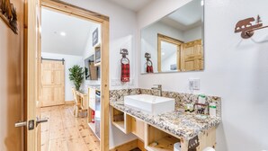 Un baño con tocador de madera, un lavabo blanco, un espejo grande y un perchero para toallas.