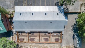 Un edificio con techo plano, varias ventanas y un espacio al aire libre cubierto con mesas y sillas.