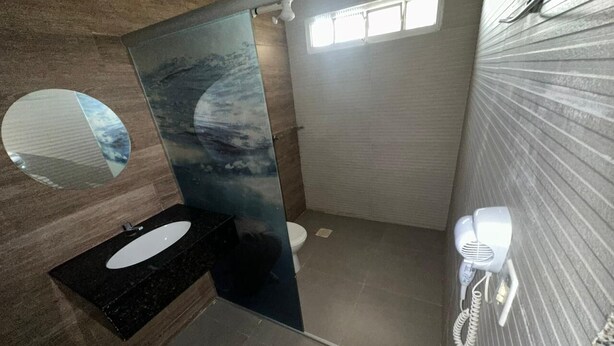 Een badkamer met een modern design, met een zwarte wastafel, toilet en een haardroger aan de muur.