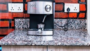 Una cafetera sobre una encimera de granito con un fondo de pared de ladrillo.
