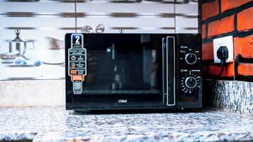 A black microwave oven on a granite countertop with a 2-year warranty sticker, a timer, and a power dial.