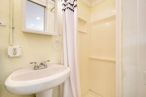 A bathroom with a white sink, a mirror, a window, and a shower curtain. - Detached Backyard Studio in Fort Lauderdale! (Fort Lauderdale)