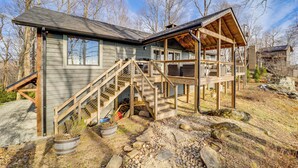 Une cabane en bois à deux étages, dotée d’un porche couvert et d’un escalier menant à l’étage supérieur.