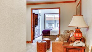 Habitación de hotel con piso de madera, un sofá, una lámpara, un teléfono y vista al exterior.