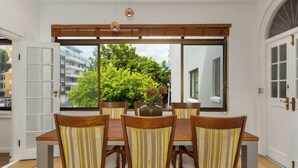 Un coin repas avec une grande fenêtre, des chaises en bois et une table.