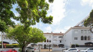 Un quartier résidentiel doté d’une entrée sécurisée, de voitures garées et d’un grand arbre.