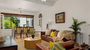 Un salon moderne avec un canapé en cuir marron, une table basse ronde en bois et un coin repas comprenant des chaises et une table en bois.