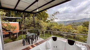 Un espace extérieur abrité comprenant un jacuzzi, des sièges et une vue sur un paysage montagneux.
