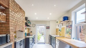 A modern kitchen with a brick wall, built-in appliances, and a view to the outside.