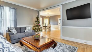 A living room with a gray sofa, a wooden coffee table, and a small Christmas tree. - Ski, Hike & Fish: Modern Rutland Home (Rutland)
