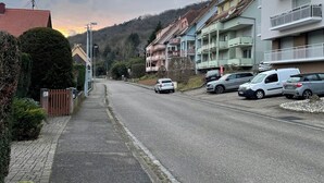Una strada residenziale con auto parcheggiate e case.
