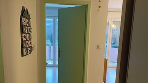Un corridoio con pavimento in legno, una porta verde e un addobbo a parete.