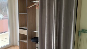 Una stanza con un armadio in legno, una sedia nera e una tenda grigia.