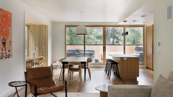 Ein modernes Interieur mit Essbereich, Küche und großen Fenstern.