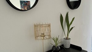 Eine schwarze Konsole mit einer goldenen Lampe, einem Topfpflanzen und einem Spiegel an der Wand.