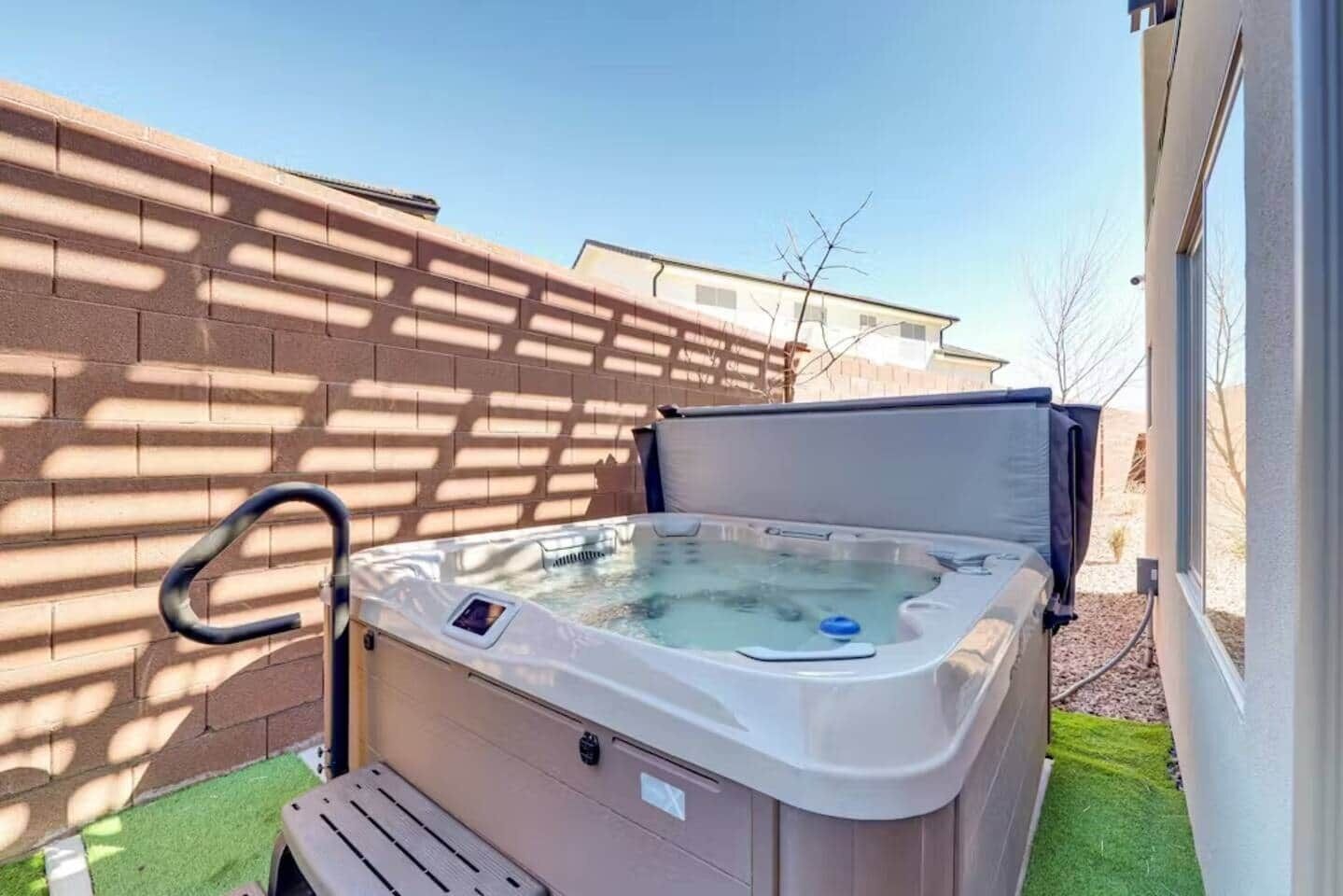 Un jacuzzi en un entorno exterior con un muro de ladrillo y cielo despejado.