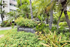 En frodig have med et skilt for Waikiki Marina Condo Hotel.
