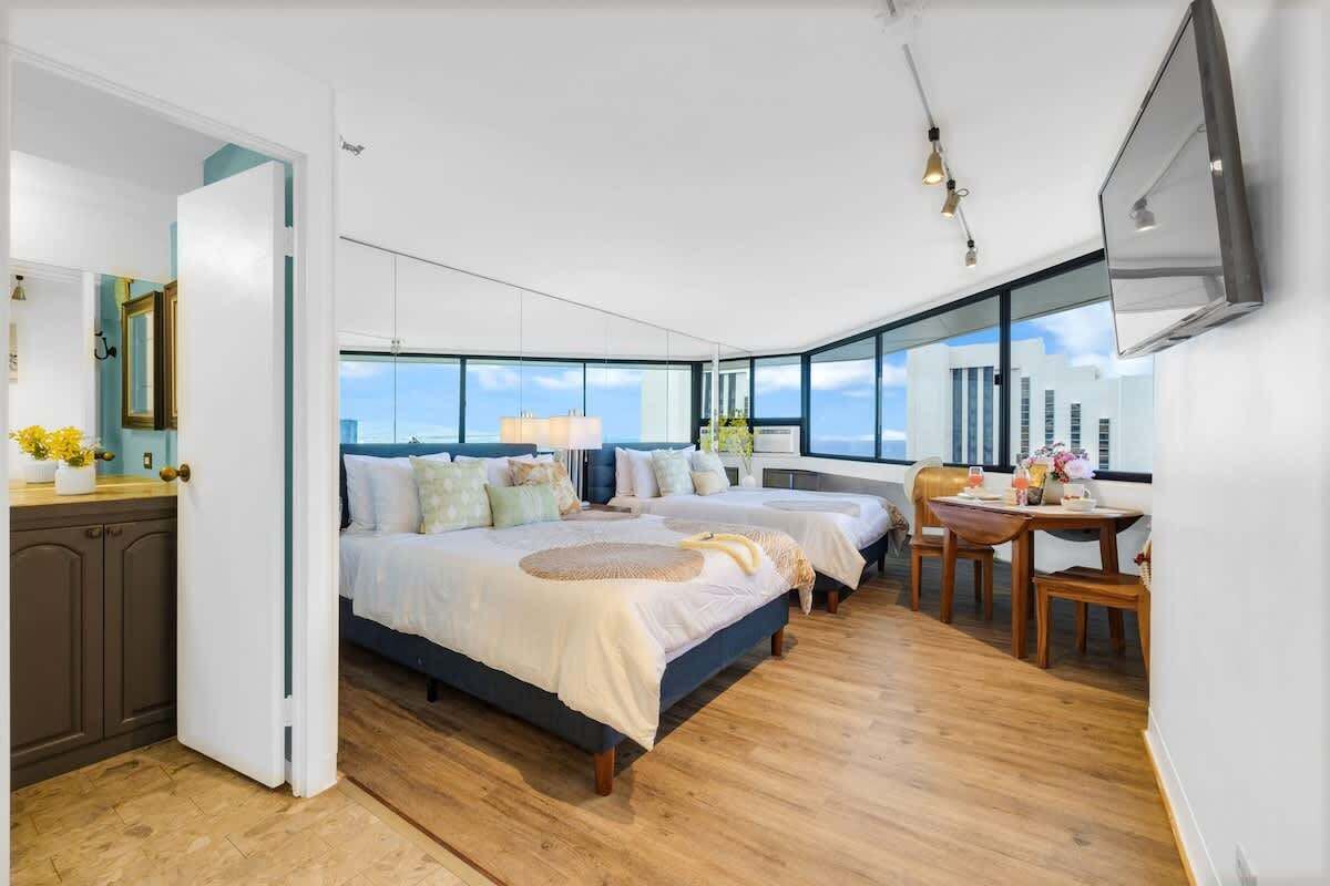 Un dormitorio moderno con una cama grande, un escritorio y vistas a la ciudad.