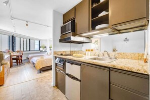 A modern kitchen with a built-in microwave, stainless steel appliances, and a granite countertop. - Waikiki Forever Ocean Views, Free Parking & Pool (Honolulu)