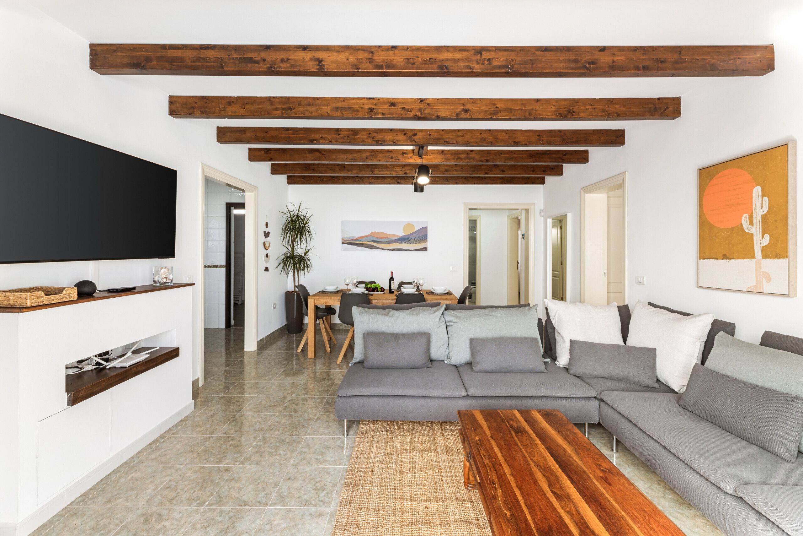 Un soggiorno moderno con un divano componibile, un tavolino in legno e una TV a schermo piatto montata a parete.