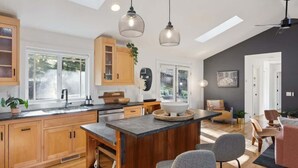 A modern kitchen with wooden cabinets, a central island, and pendant lighting. - Ravenwood Paradise: Private Pool and Hot Tub (Glen Ellen)
