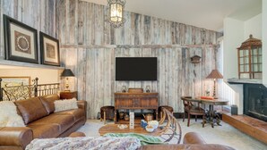 A living room with a wooden wall, a sofa, a coffee table, and a fireplace. - Vail Vista Mountain Retreat w/ Balcony & Views, Near Vail Ski Village (Vail)