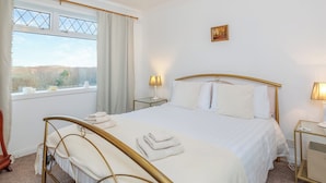 Una camera d'albergo ordinata con un letto, comodini, una finestra con tende e vista sull'esterno.