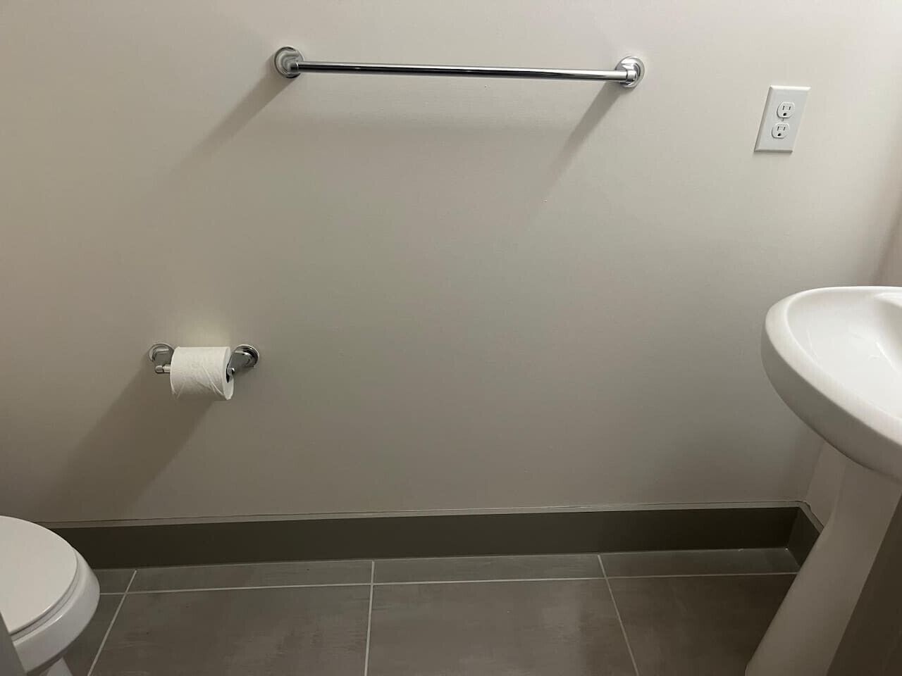 Une salle de bain équipée de toilettes, d’un porte-serviettes et d’un lavabo.
