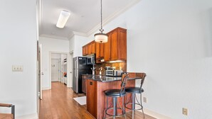 Una cocina moderna con armarios de madera, una isla central con taburetes de bar y un refrigerador de acero inoxidable.