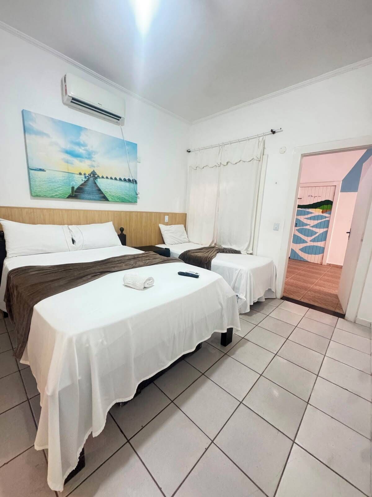 Quarto de hotel com duas camas, um quadro, ar condicionado e vista para o exterior.