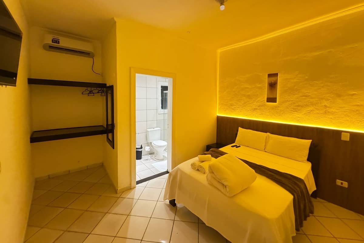 A hotel room with a bunk bed, a bedside table with towels, and a bathroom visible through an open door.