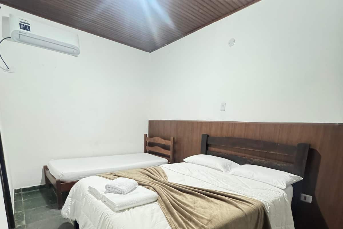 A hotel room with two beds, a wooden headboard, a tiled floor, and a ceiling light.