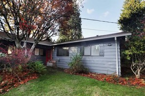 A single-story house with a red door, a small front porch, and a well-maintained lawn.