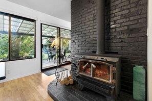 A modern living room with a large fireplace, a glass door leading to an outdoor patio, and a wooden floor.