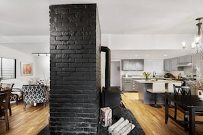 A modern kitchen with grey cabinets, a central island, and a black brick accent wall.