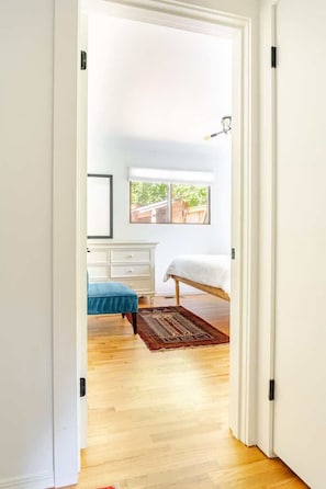 A bedroom with a bed, a dresser, a window, and a door.