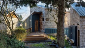 A modern house with a wooden exterior, a front porch, and a small garden area. - Deck Views, Fire Pit, Pool, 3 Mins to Beach Madrona Tree Retreat by Avantstay (Coupeville)