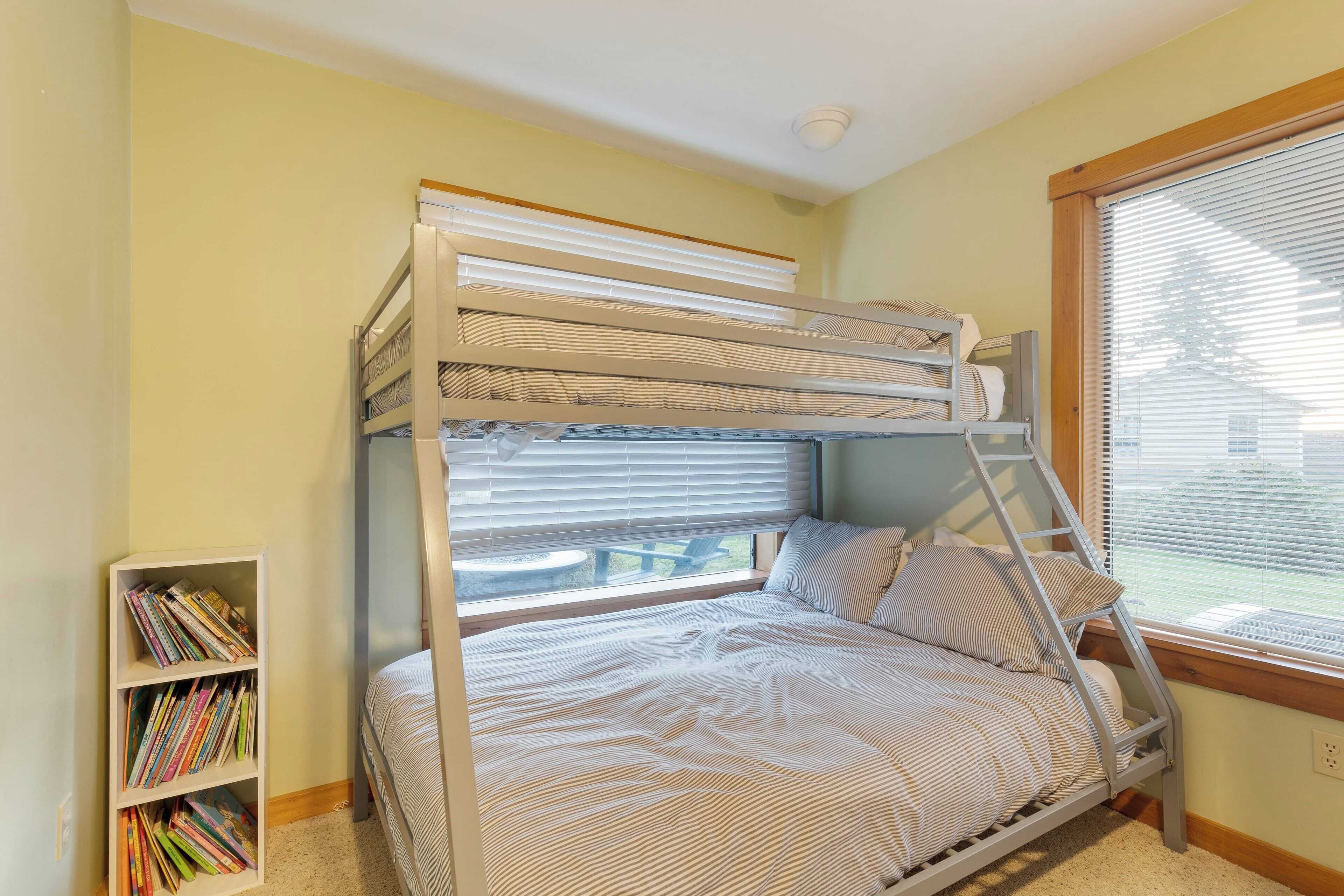 A bunk bed with a ladder, a bookshelf, and a window with blinds.