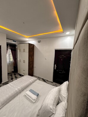 A bedroom with a bed, a wardrobe, and a door. - The Paletinos Luxury Aparthotel  (Umuahia)