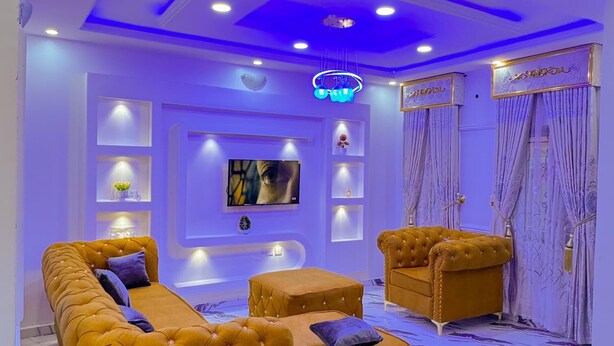 Un salon moderne avec un ensemble de canapés, un téléviseur et un éclairage décoratif.