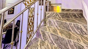 Un escalier en marbre, agrémenté de rampes en métal ouvragé, mène à l’étage supérieur.