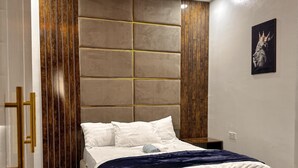 Une chambre à coucher moderne avec un grand lit, un sol en marbre et une tête de lit en bois.