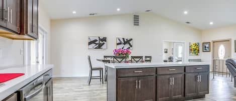 Una cocina amplia con armarios de madera oscura, una isla central y una zona de comedor con sillas y una mesa.