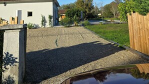 A house with a red-tiled roof, a gravel driveway, and a wooden fence. - Villa Martic in Biscarrosse (Biscarrosse)