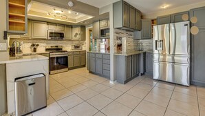 A modern kitchen with stainless steel appliances, grey cabinets, and a tiled floor. - Private Pool, Grill & Fenced Yard: Las Vegas Home (Las Vegas)