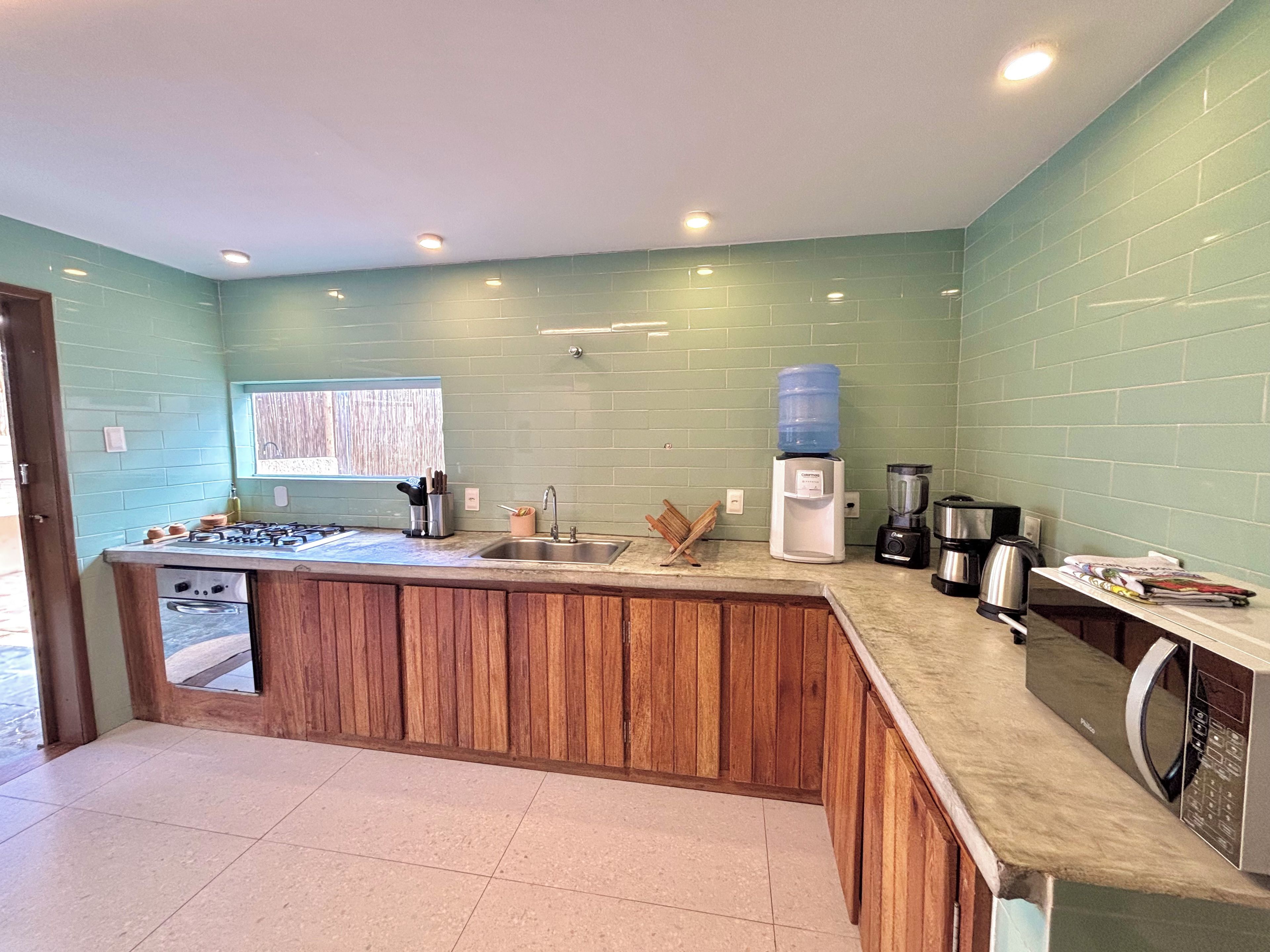 A kitchen with a wooden island, a water dispenser, and a coffee maker.